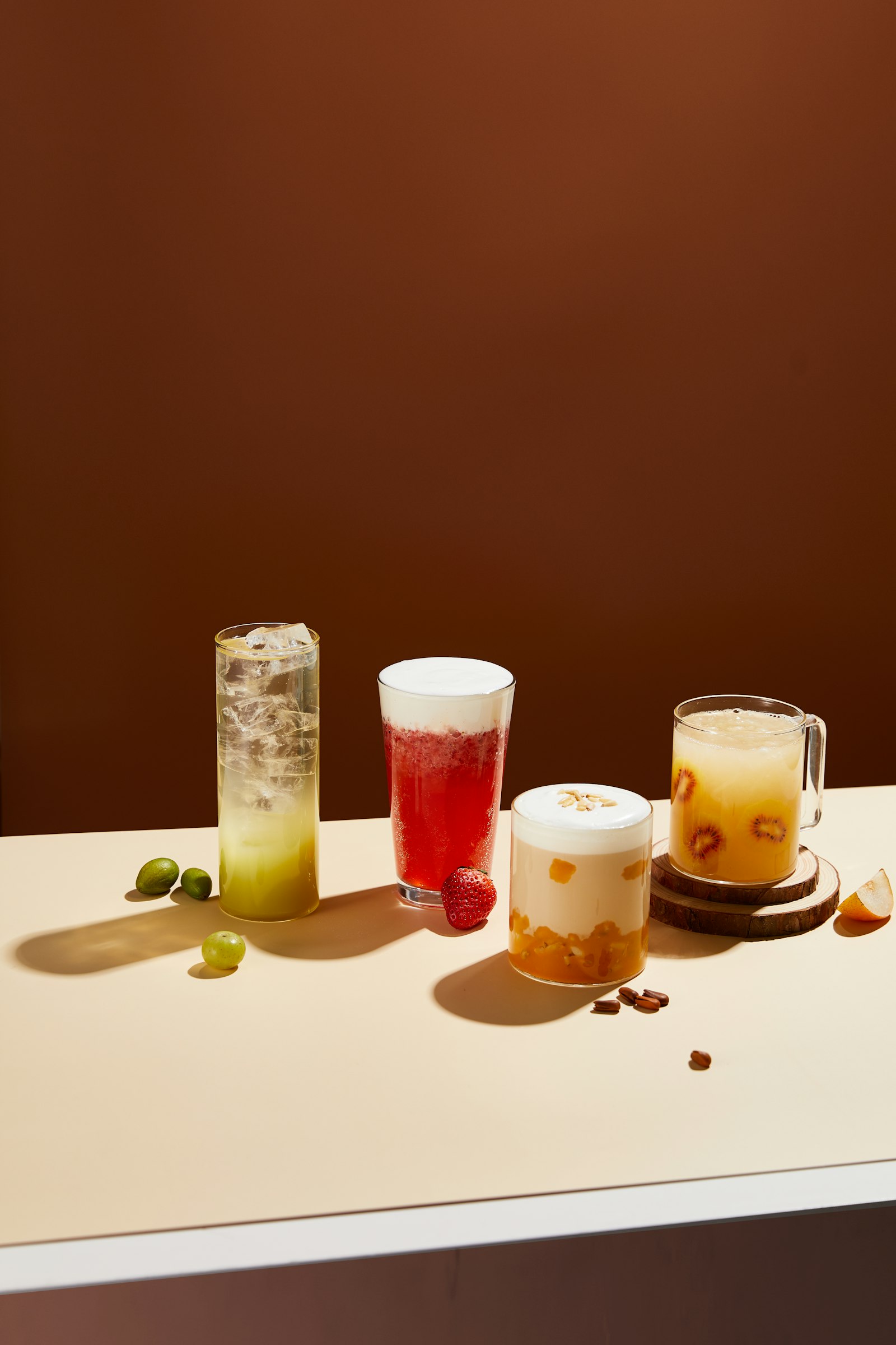 Several fruit teas and milk teas in glasses lined up on a cream table